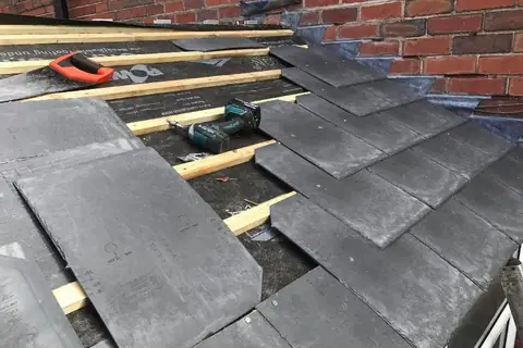 Slate-effect tiles being fixed to new battens